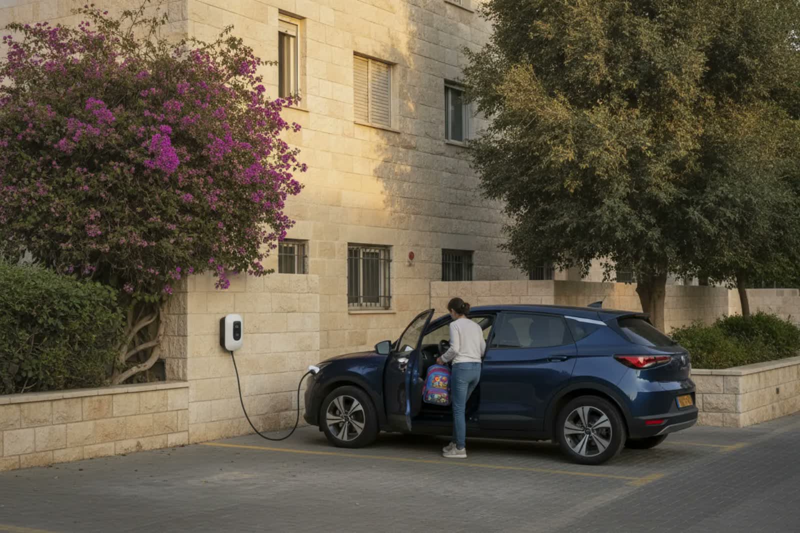 רכב חשמלי נטען בעמדה ביתית בחניה של בניין מגורים בישראל